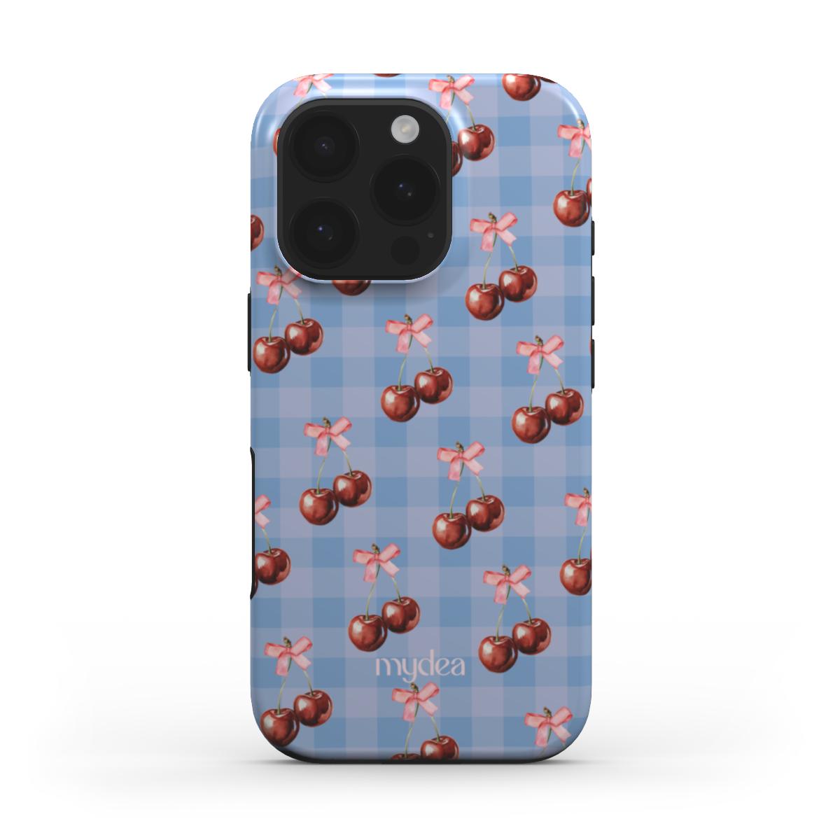 Cover MagSafe con pattern ciliegie e fiocchi rosa su sfondo vichy azzurro – stile babycore e dolce.